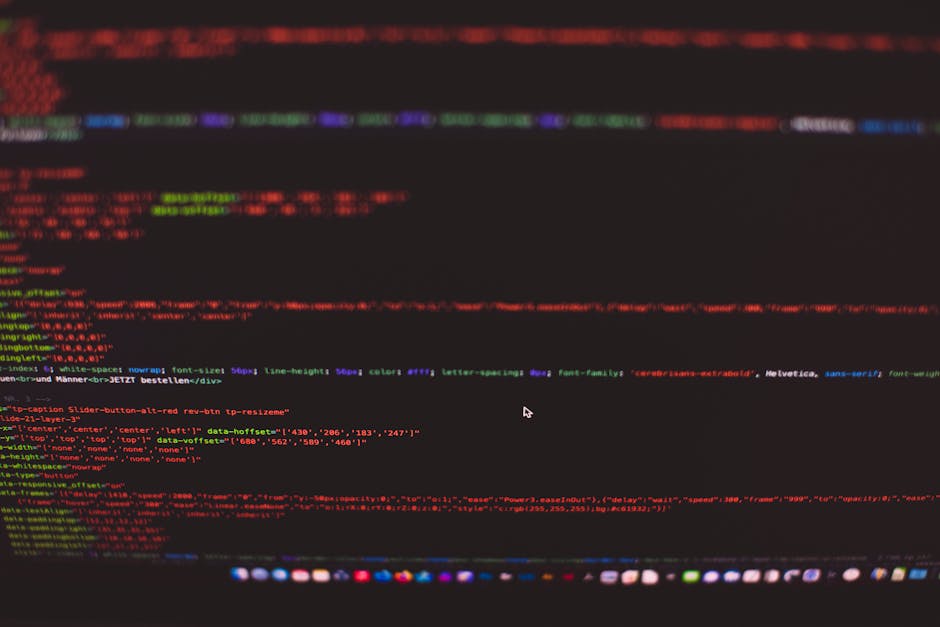 A close-up view of a computer screen displaying a code editor with lines of HTML and CSS code in various colors such as red, green, purple, and blue on a dark background. The text includes tags, attri